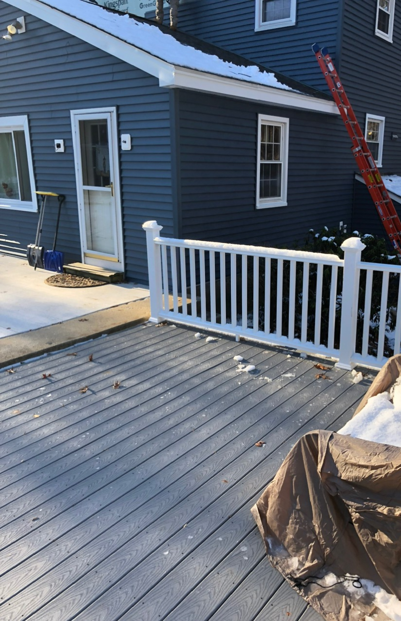 Completed composite deck and blue vinyl siding installation by McCarthy Exteriors LLC in Southern New Hampshire during winter season