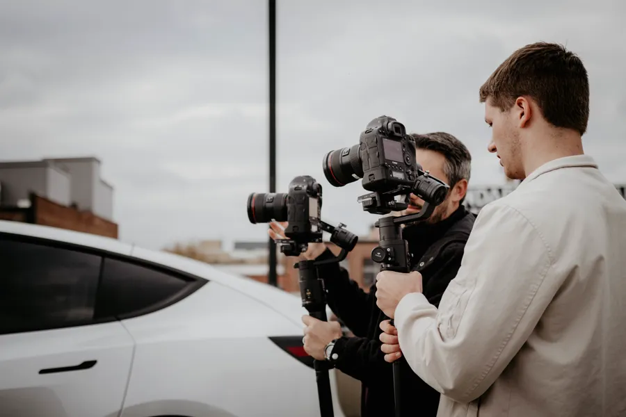 Two filmmakers running a gimbal shot on a rooftop