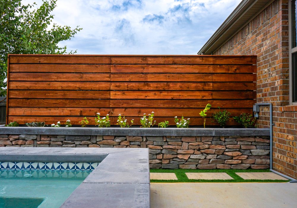 Cedar privacy screen over a stone planter wall