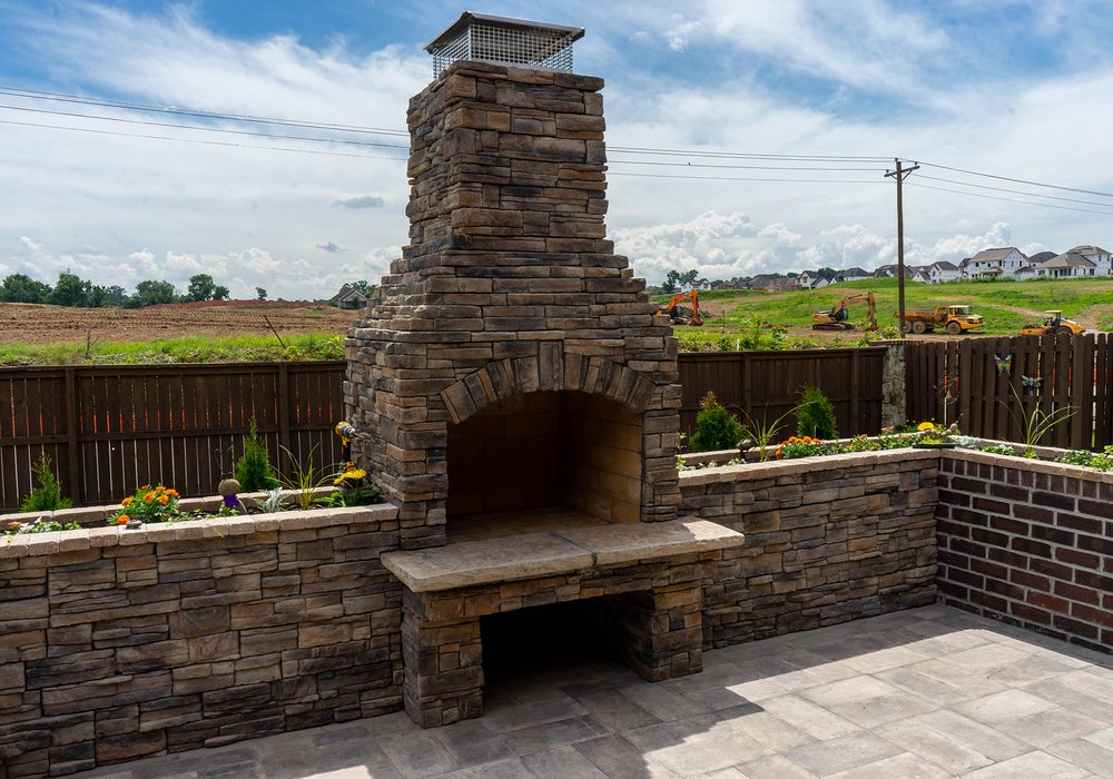 Stacked stone outdoor fireplace on a paver patio