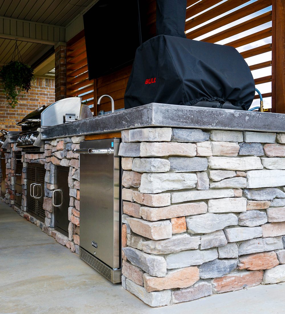 Stacked stone outdoor kitchen island with a concrete top