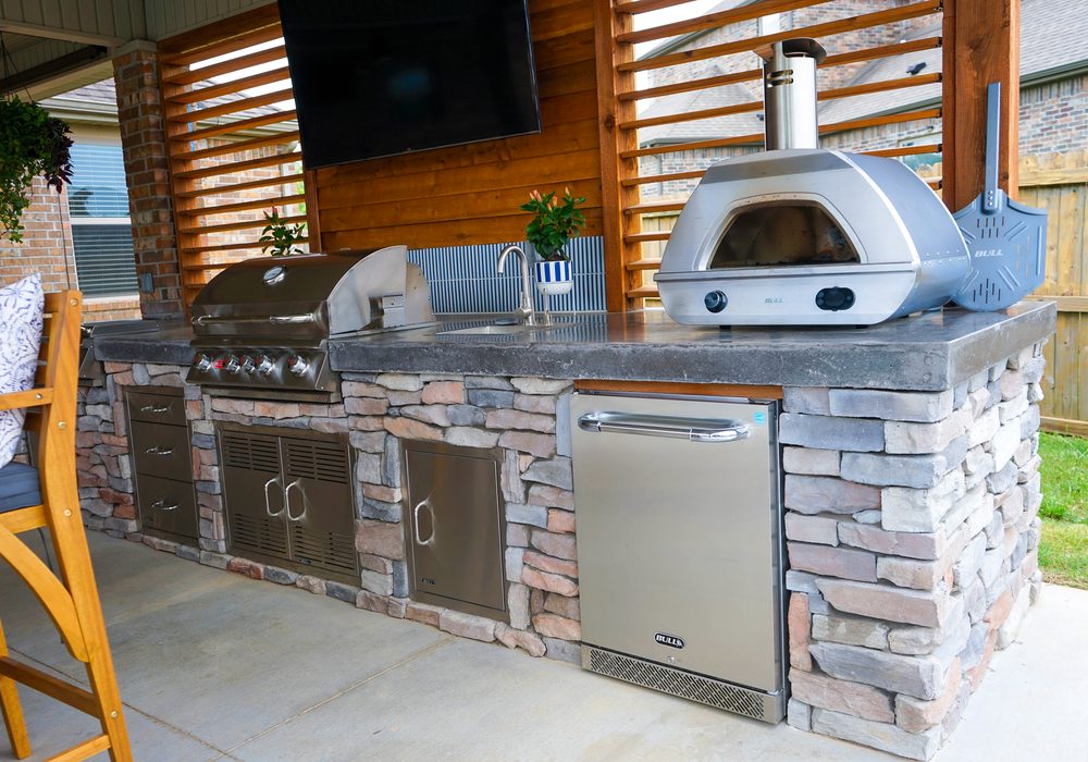 Stone outdoor kitchen with pizza oven under a covered patio