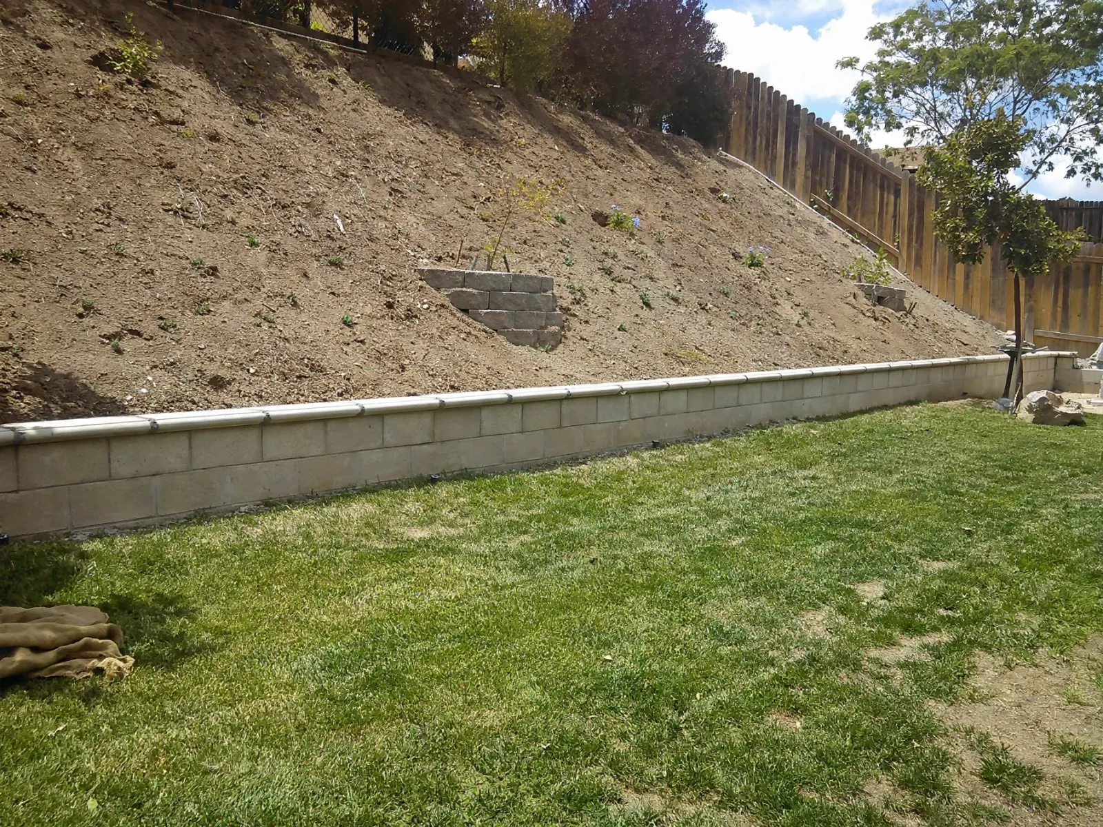 Block retaining wall holding a slope above a lawn