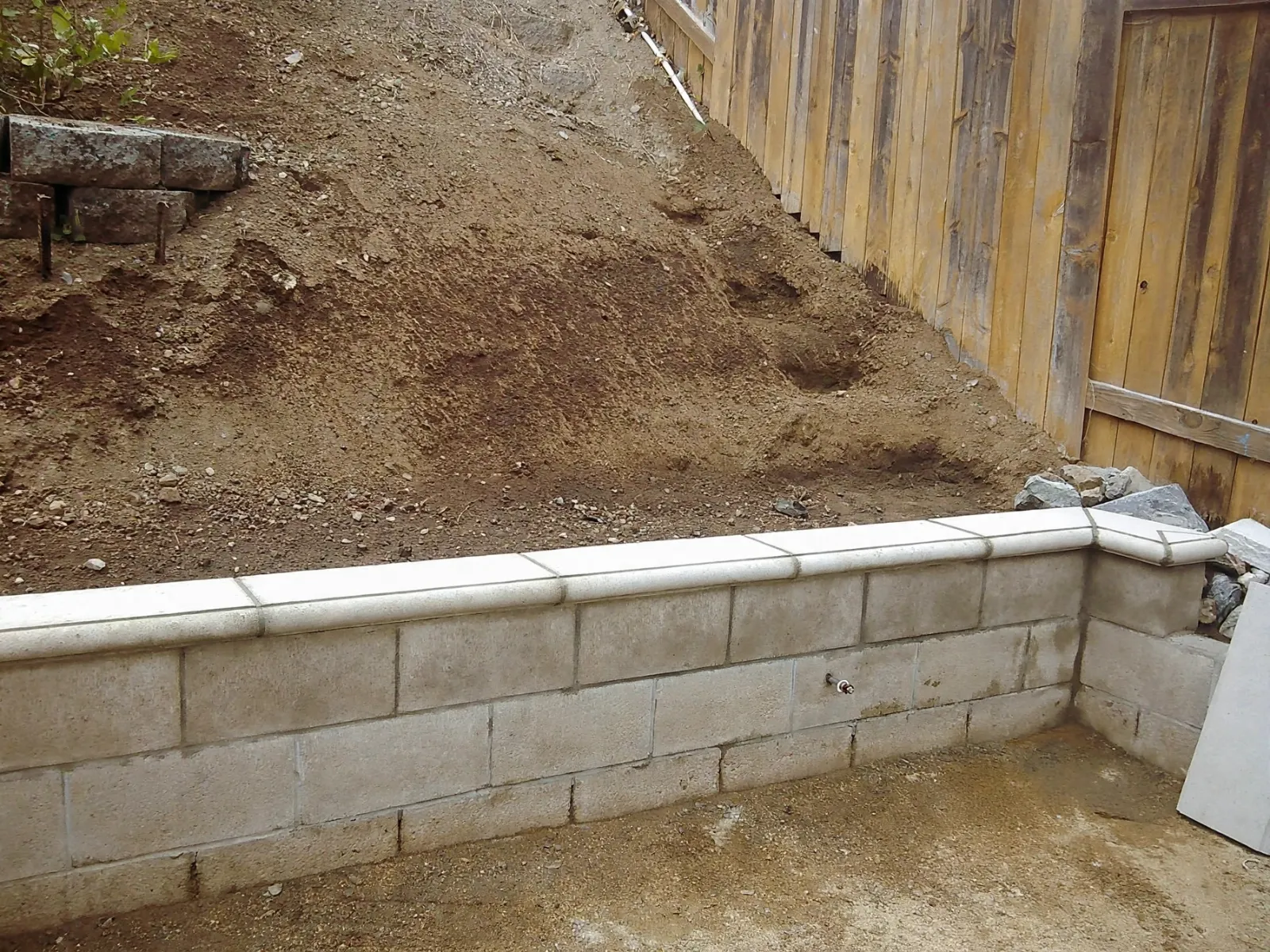 Corner of a capped block retaining wall at a wood fence