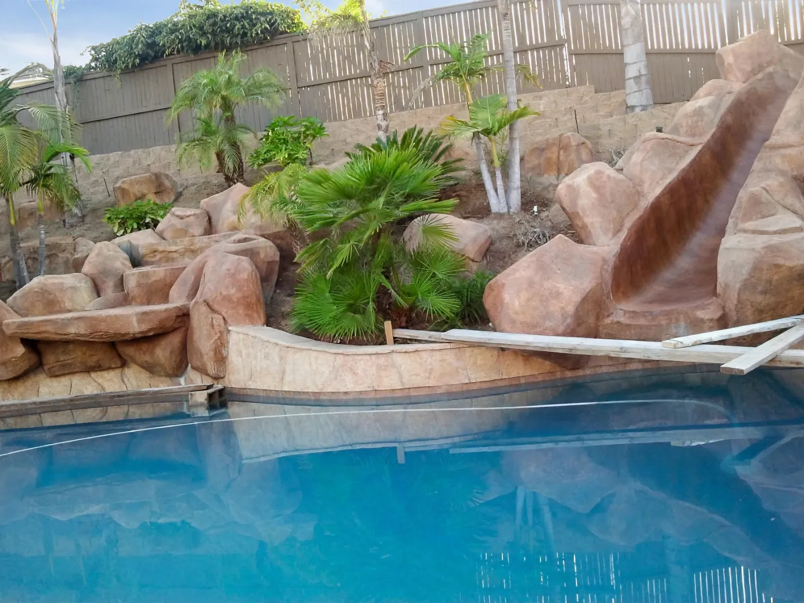 Faux rock pool slide built into a planted hillside above a pool