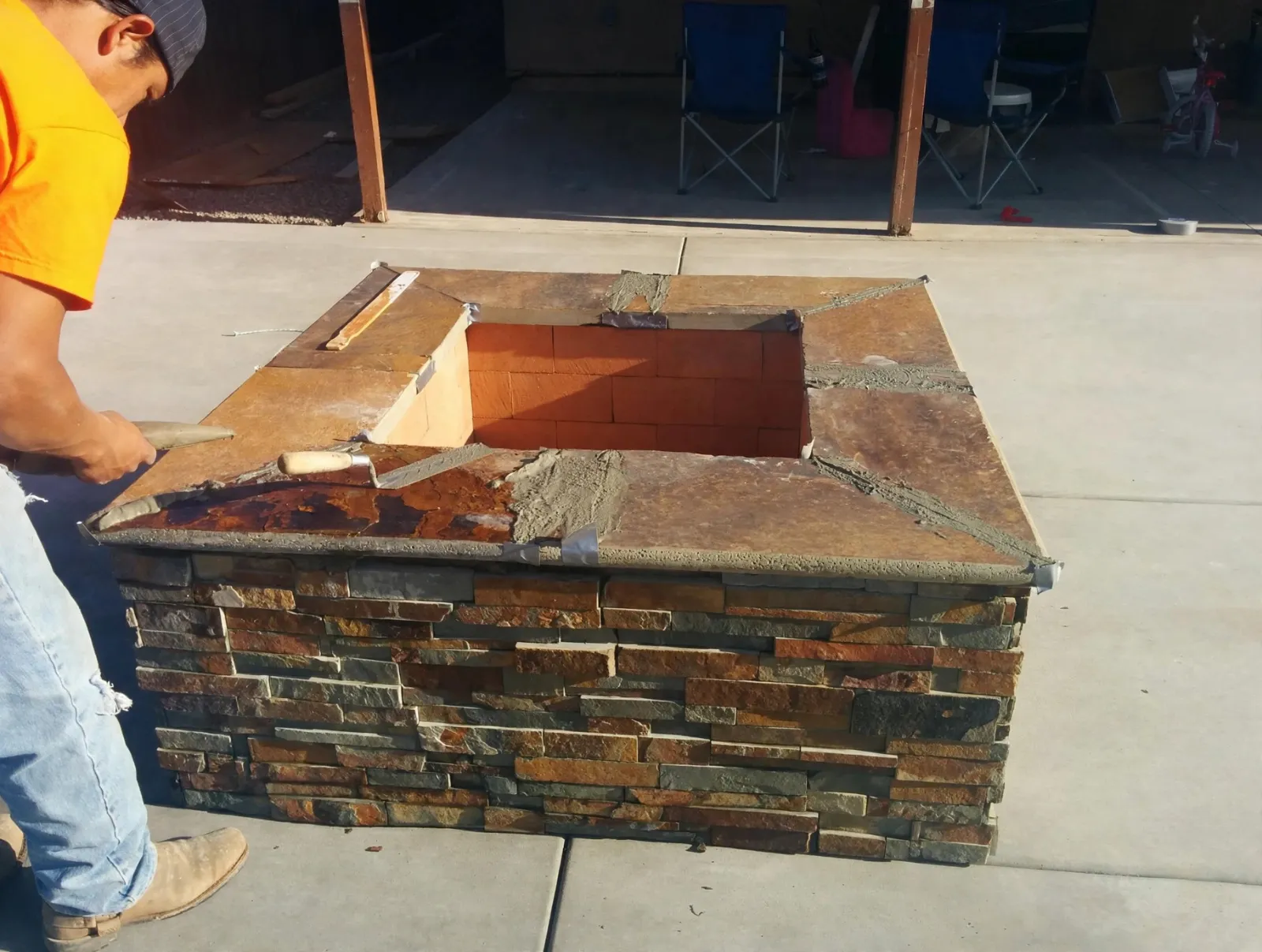 Stone cap being set on a stacked stone fire pit