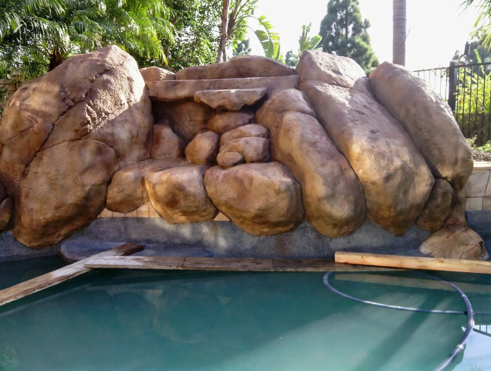 Stacked faux boulders forming a grotto at the edge of a pool
