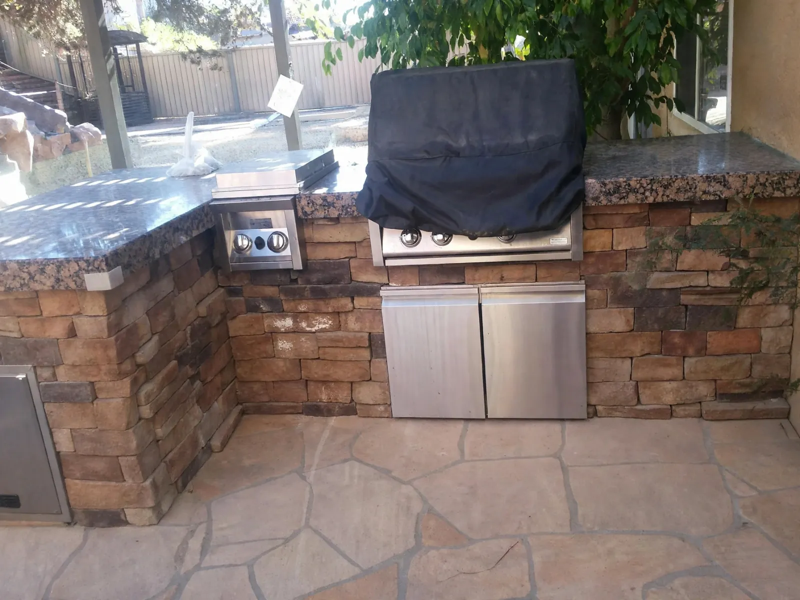 Flagstone patio in front of a stone veneer grill island
