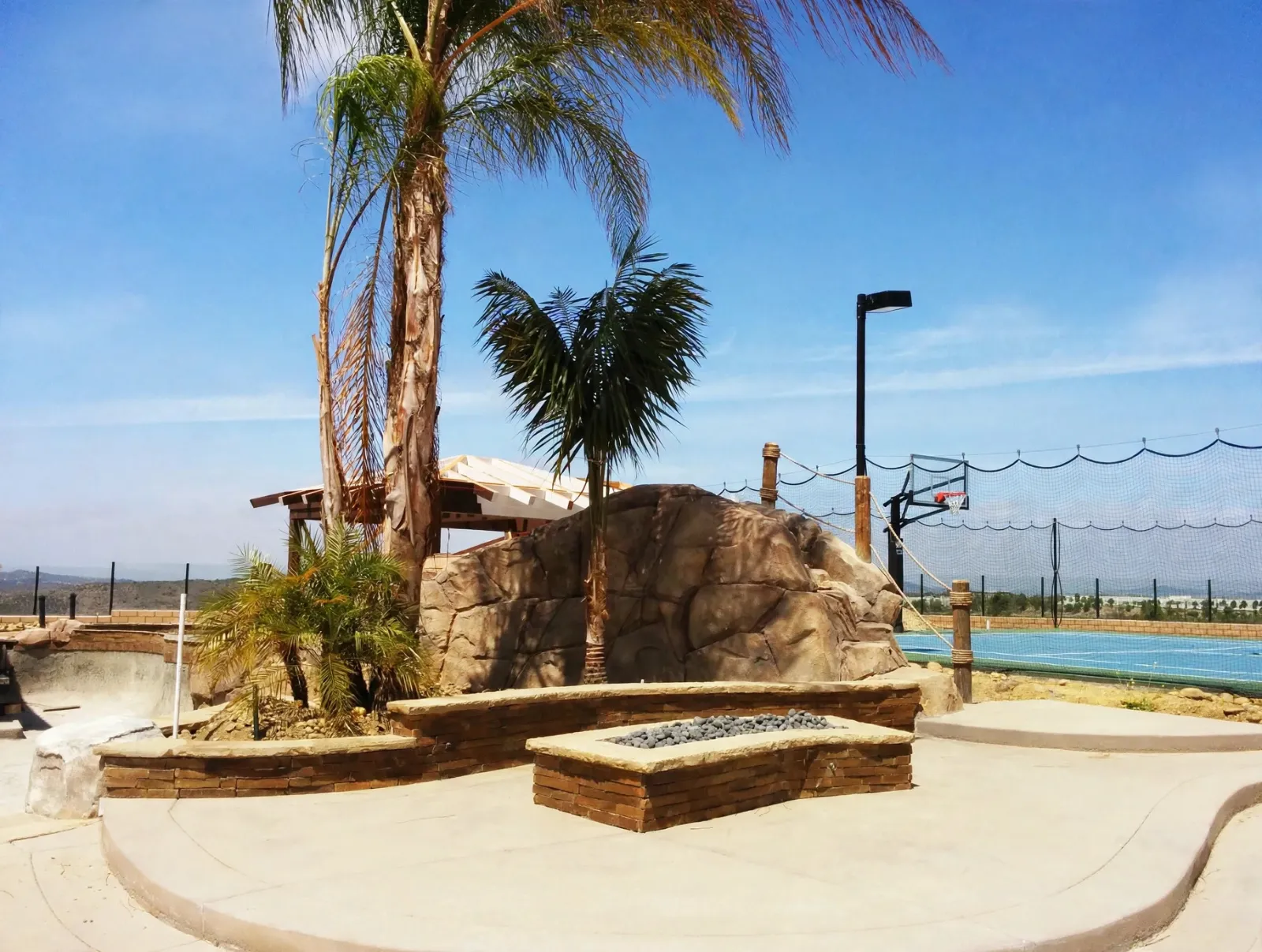 Fire pit filled with lava rock on a curved concrete patio