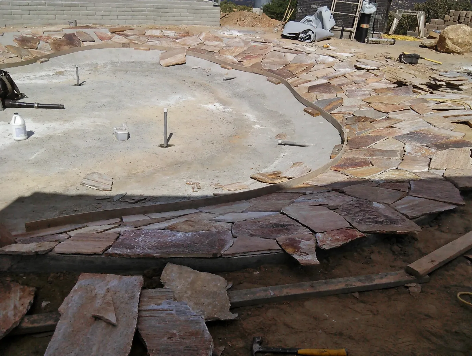 Flagstone pieces being fitted around a curved concrete pad