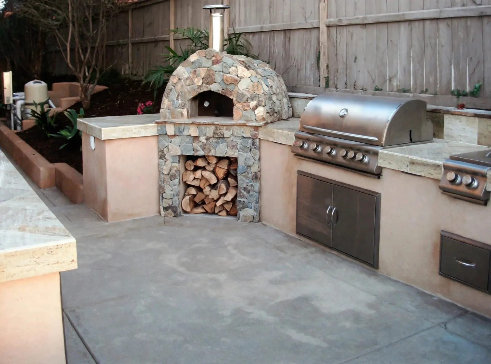Outdoor kitchen with a stone pizza oven and a built-in grill