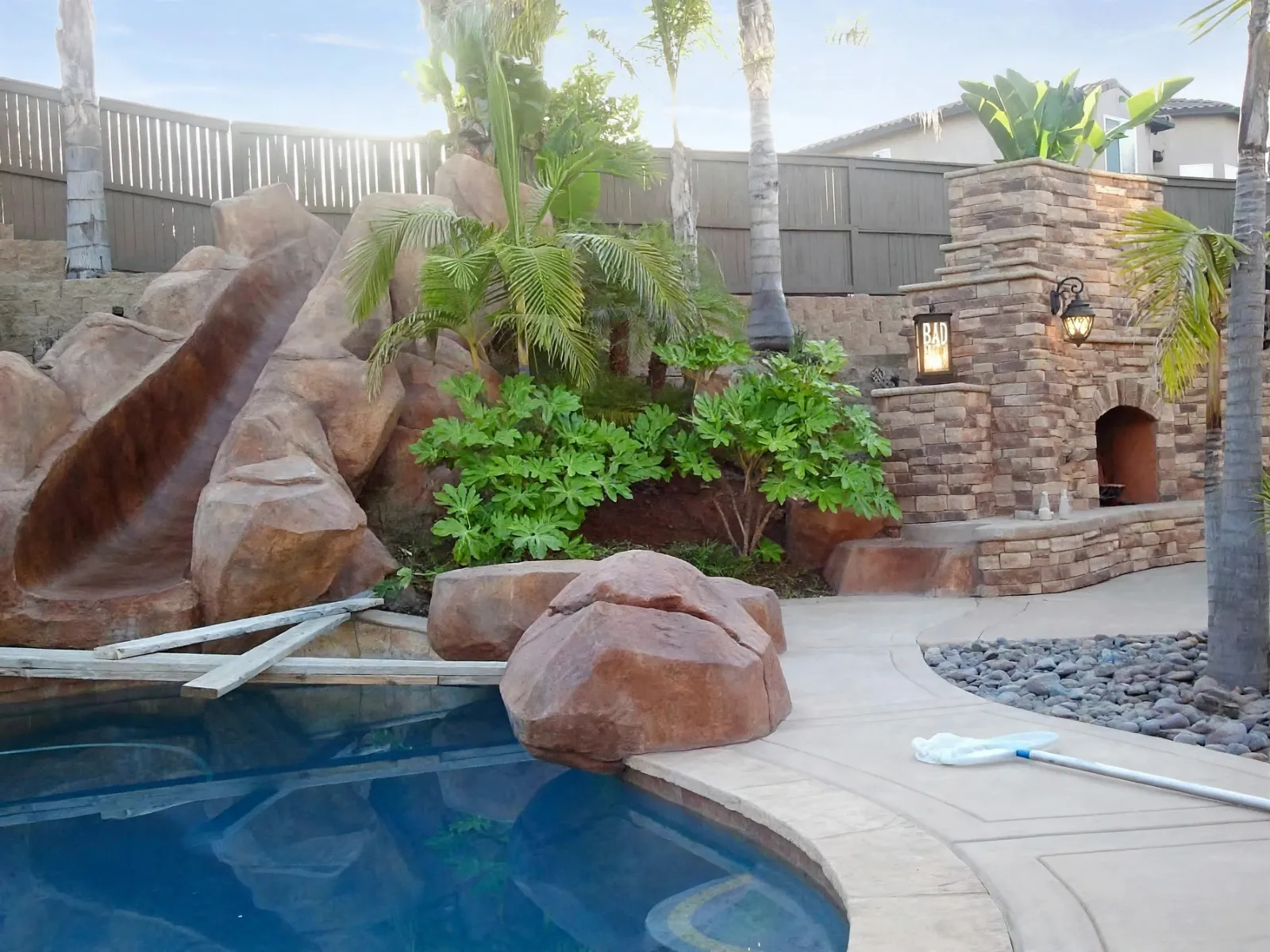 Pool deck with a faux rock slide and a stone outdoor fireplace
