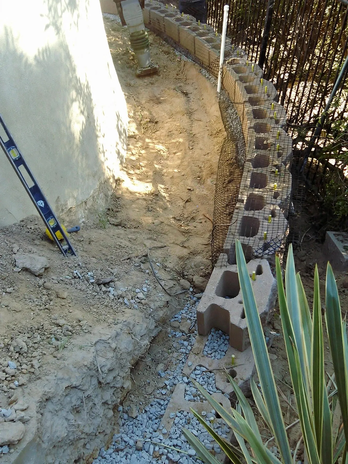 Retaining wall under construction with drainage rock behind it