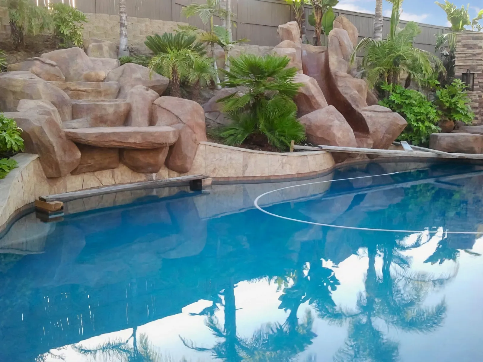 Faux rock waterfall and slide along the edge of a swimming pool