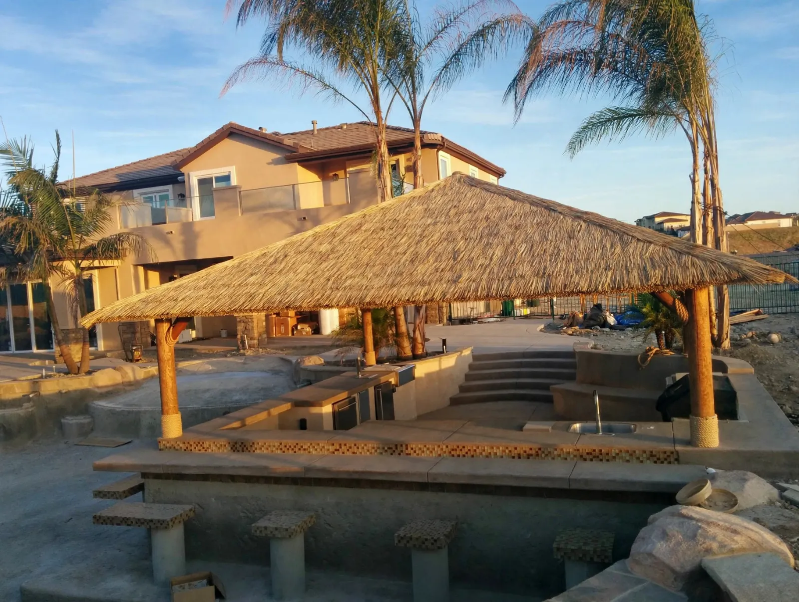 Palapa-covered outdoor kitchen beside a pool
