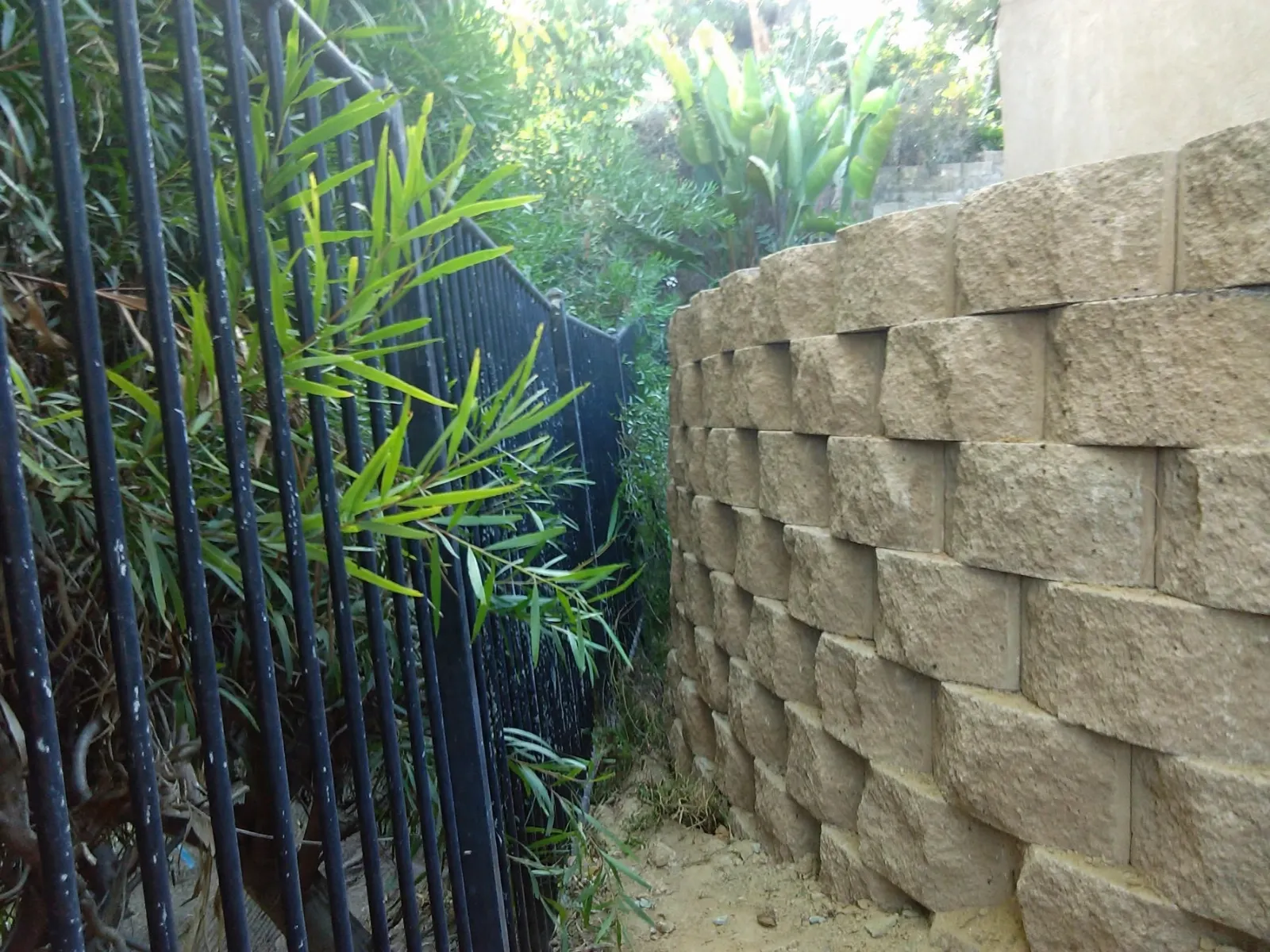 Split-face block retaining wall beside an iron fence