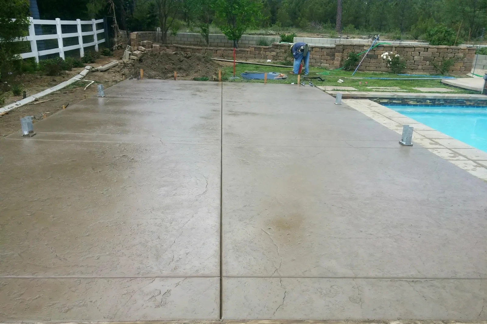 Wide concrete pool deck with saw-cut joints beside a pool