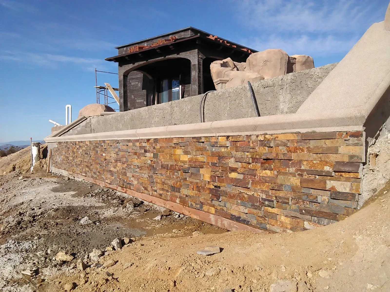 Retaining wall faced in stacked stone veneer on a hillside lot