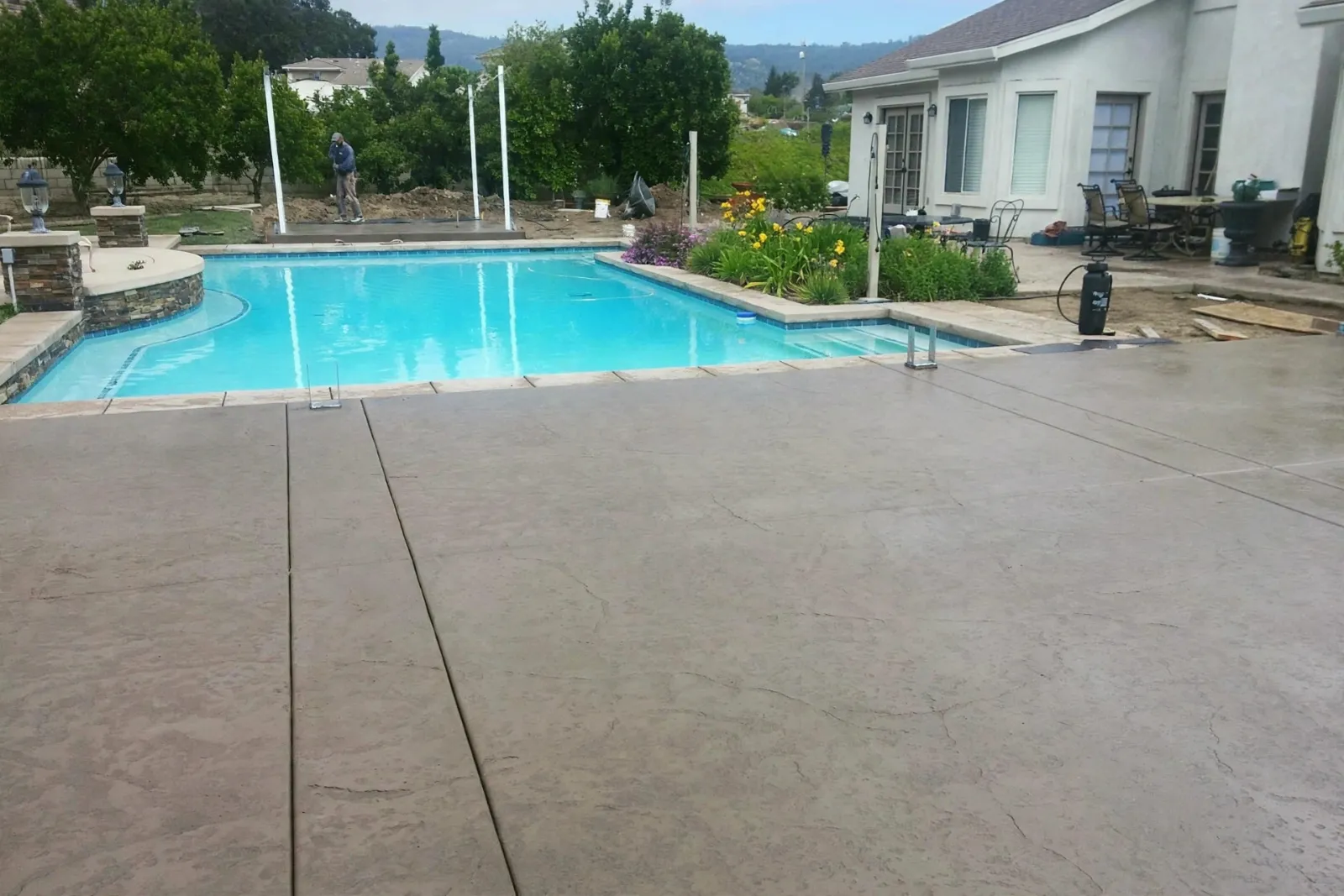 Concrete pool deck running along a swimming pool toward a house