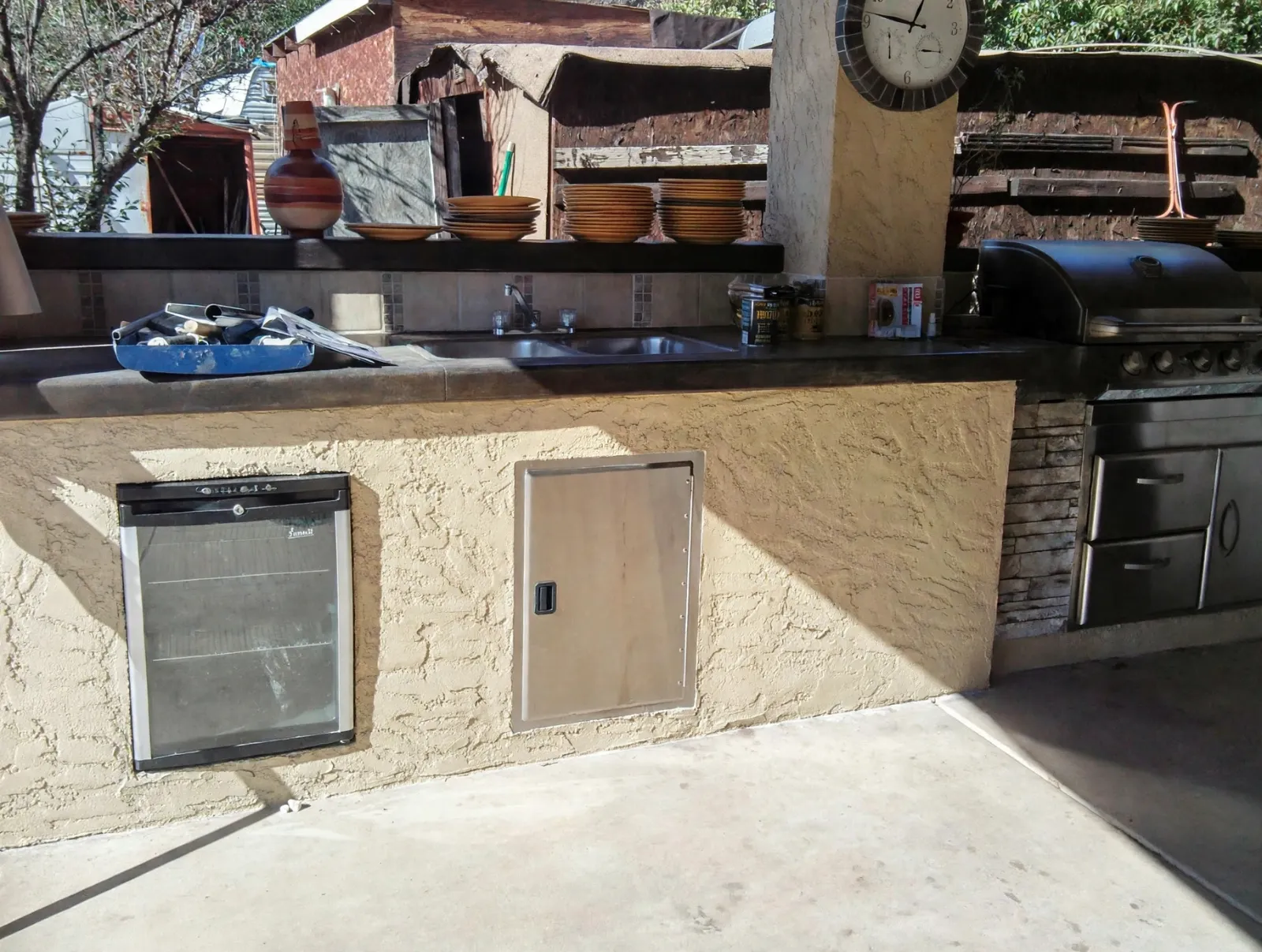 Stucco outdoor kitchen bar with a sink, fridge and grill