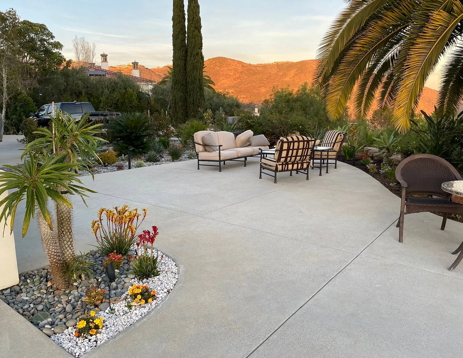Curved concrete patio with a planter bed and seating, mountains at sunset