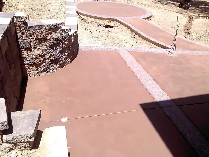 Split-face block retaining wall beside colored concrete walkways