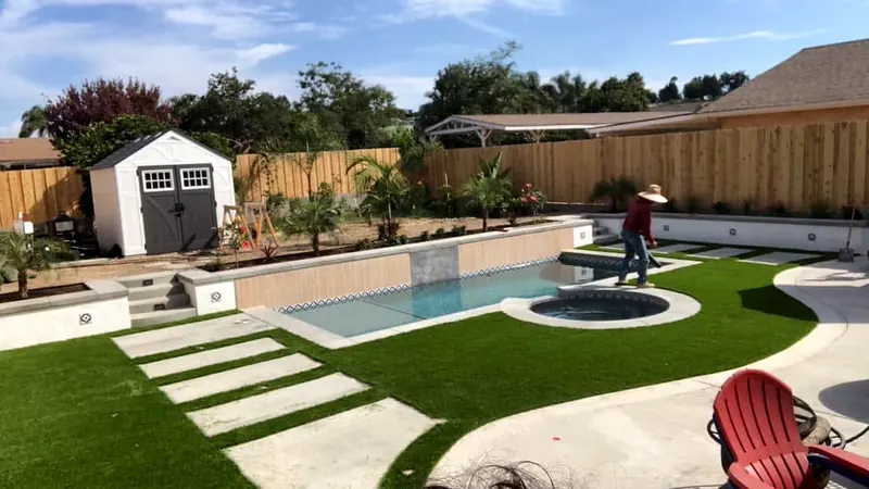 Backyard pool and spa with concrete stepping pads and turf