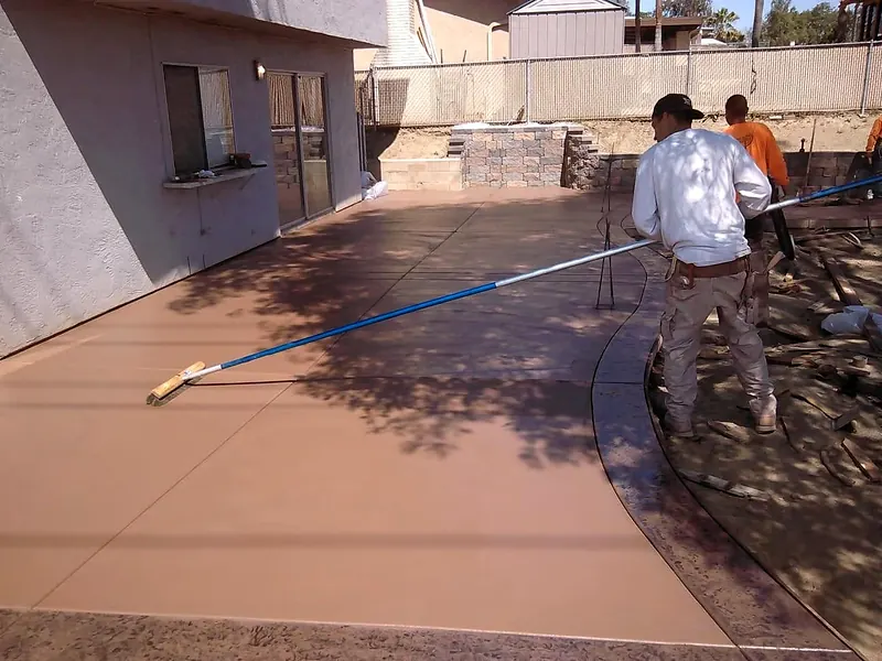 Finisher floating a colored concrete patio