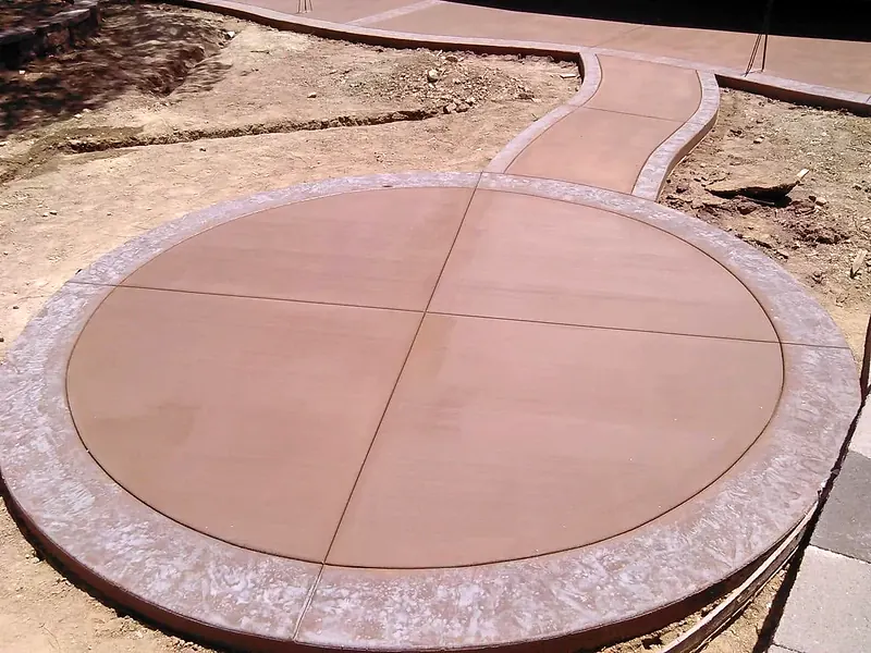 Round colored concrete patio with a stamped border and a curved walkway