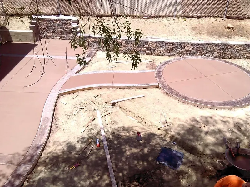 Colored concrete walkway, round patio and block retaining wall
