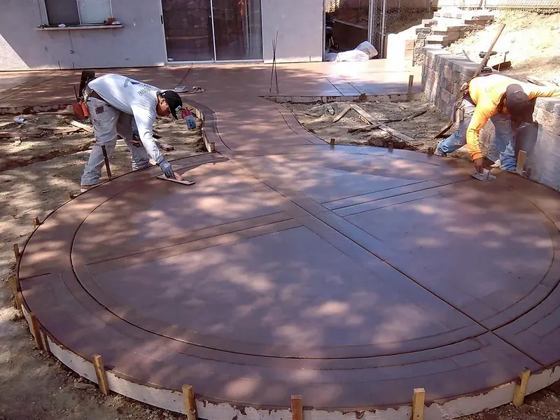 Crew troweling a round colored concrete patio