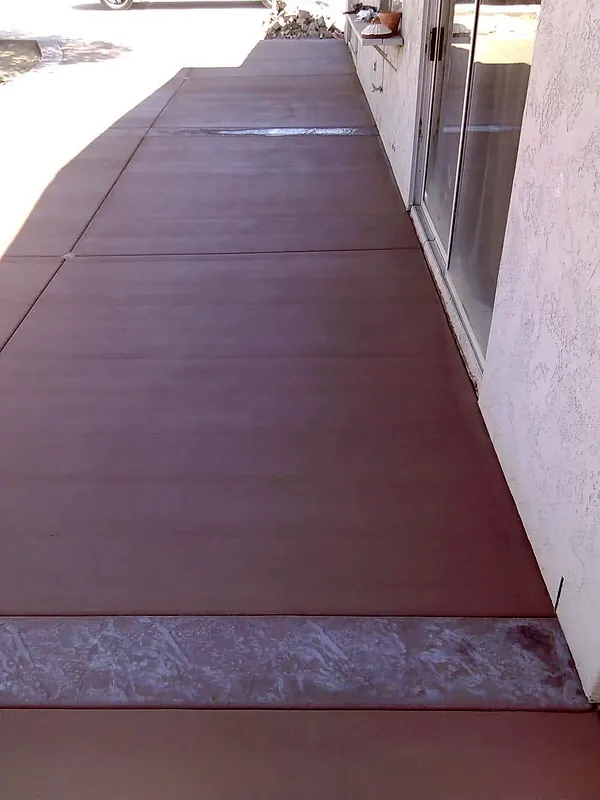 Colored concrete walkway with a stamped accent band along a house