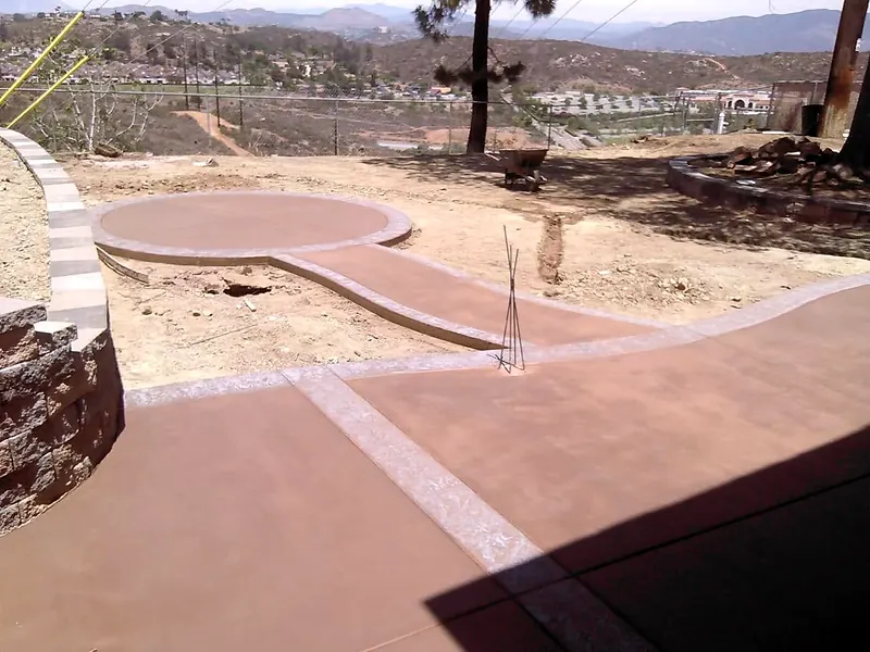 Colored concrete walkway leading to a round patio with a valley view