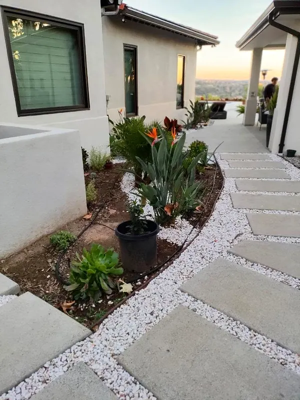 Concrete stepping pads set in white gravel beside a planted bed