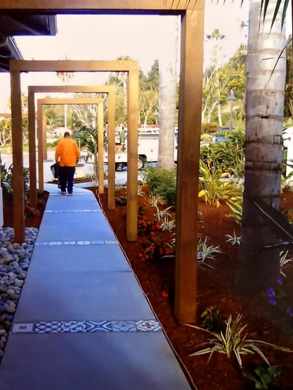 Concrete walkway with tile inlay bands under a timber arbor