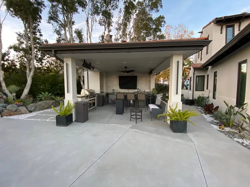 Covered outdoor kitchen pavilion on a broom-finished concrete patio