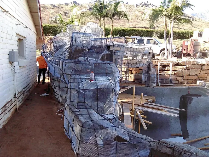 Mesh frame for a faux rock wall going up beside a pool