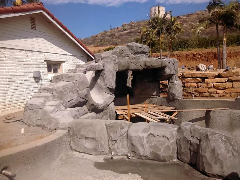 Carved faux rock grotto wrapping a pool shell before staining