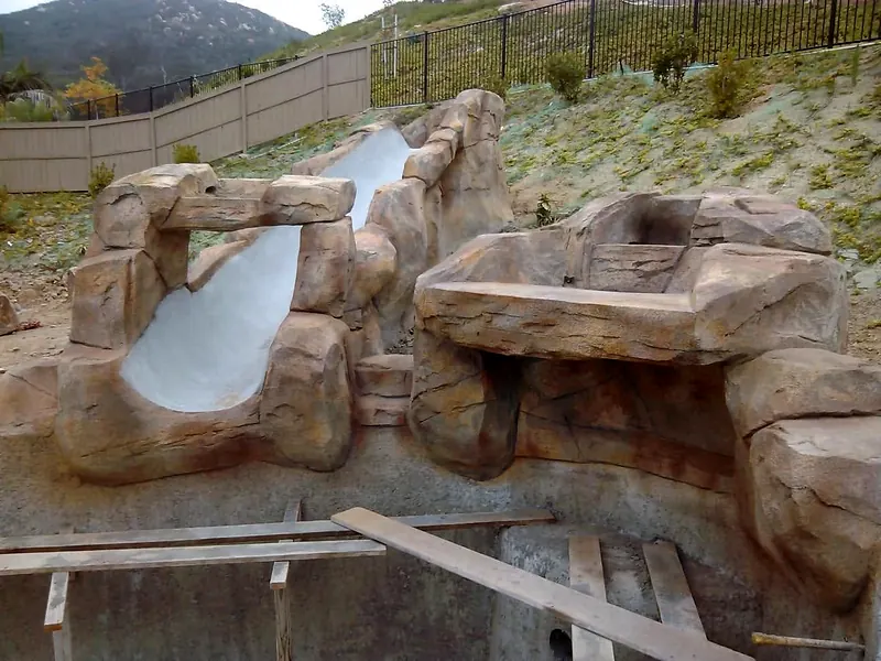 Faux rock slide and waterfall shelf built over a pool shell