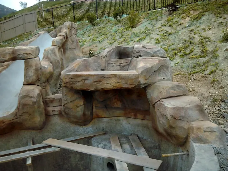 Stained faux rock waterfall and slide above a pool shell