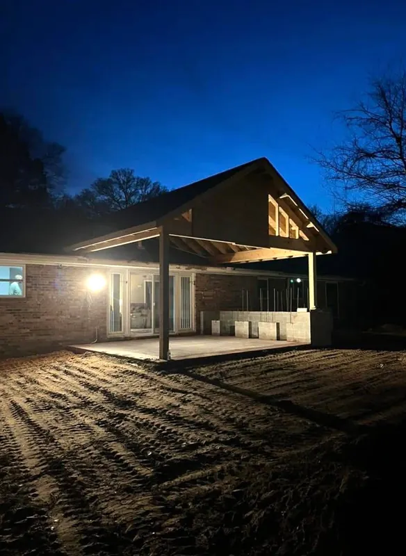 Gable patio cover on a brick house, lit at night