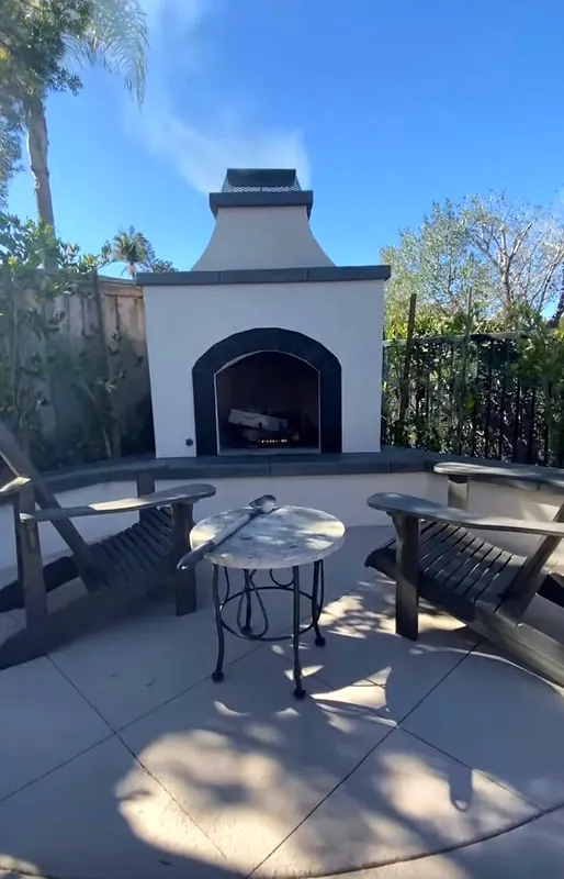 Stucco outdoor fireplace on a curved concrete patio with a seat wall
