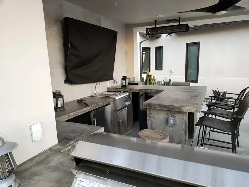 Outdoor kitchen with concrete counters and stainless appliances under a patio cover