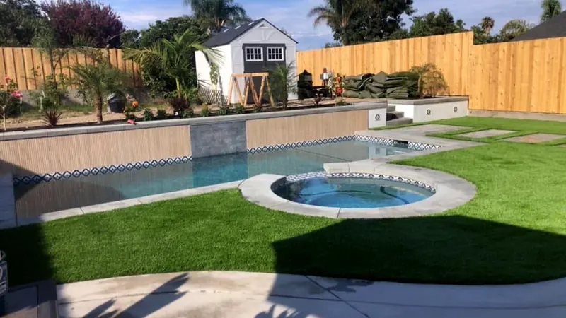 Pool with a raised tile-band wall and a round spa with concrete coping