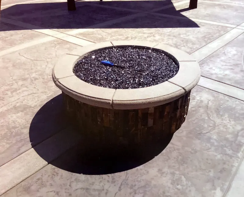 Round fire pit with a concrete cap on a stamped concrete patio