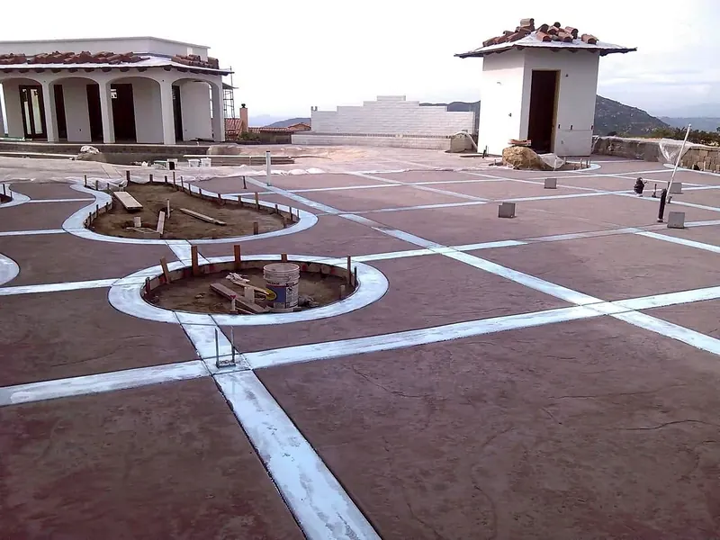 Stamped concrete courtyard with a banded grid and planter rings