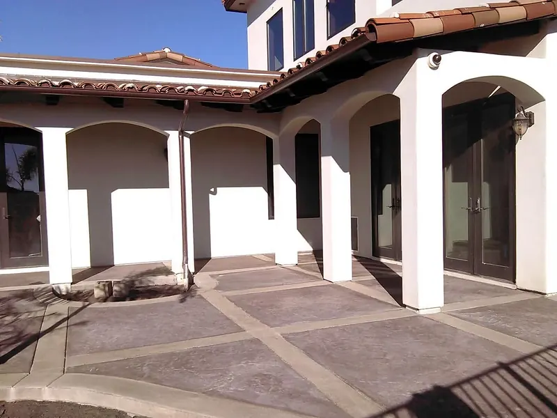 Stamped concrete courtyard with smooth bands along an arched colonnade