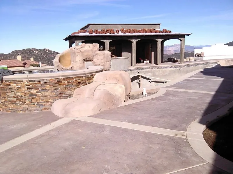 Stamped concrete deck with a stacked-stone raised spa and a faux rock slide