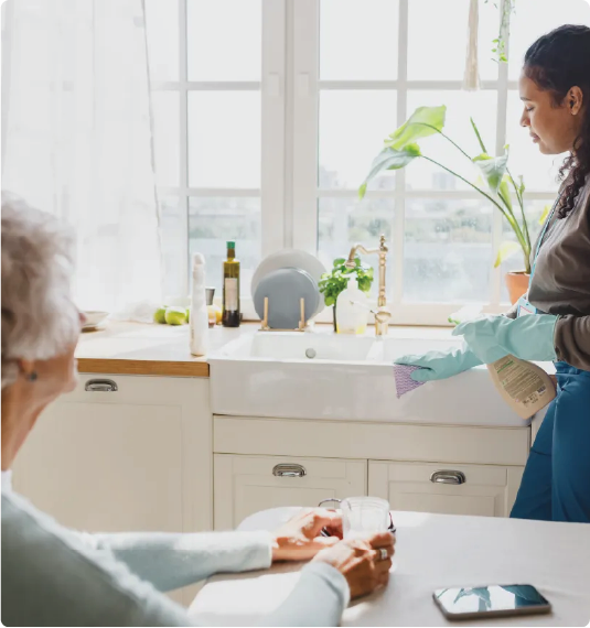 A white young lady cleaning a kitchen counter in a lighted room