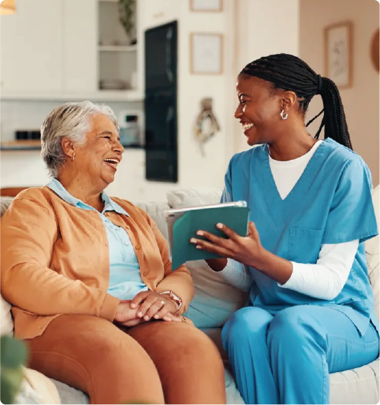 A elderly colored lady laughing with a dark nurse